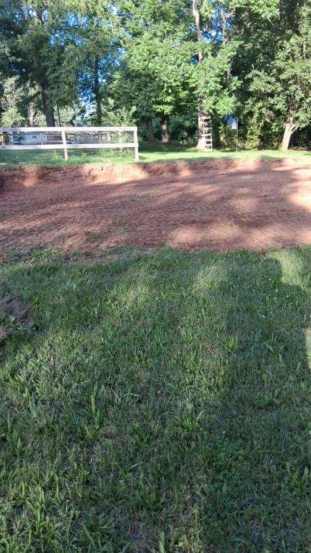 Rough-graded pool site in Stoneville viewed from the lawn toward the fence